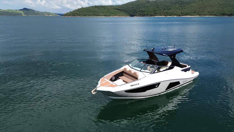 Slide: The Image of 2025 Ventura V300 Crossover boat on a serene lake with lush green hills. - 6