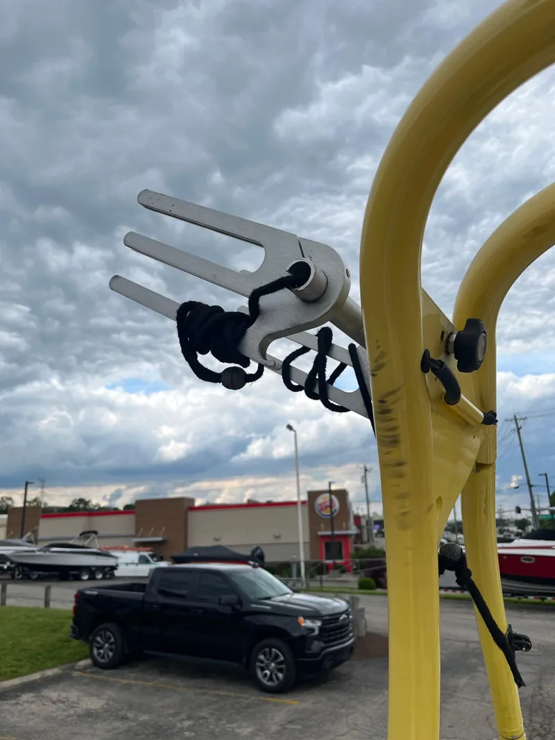 Slide: The Image of Yellow boat tower with rope, cloudy sky, and parked vehicles in the background. - 22