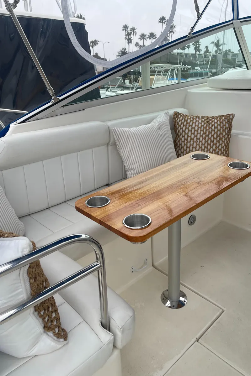 Slide: The Image of 1992 Ocean Yachts Sport Cruiser interior with cushioned seating and wooden table, featuring cup holders. - 12