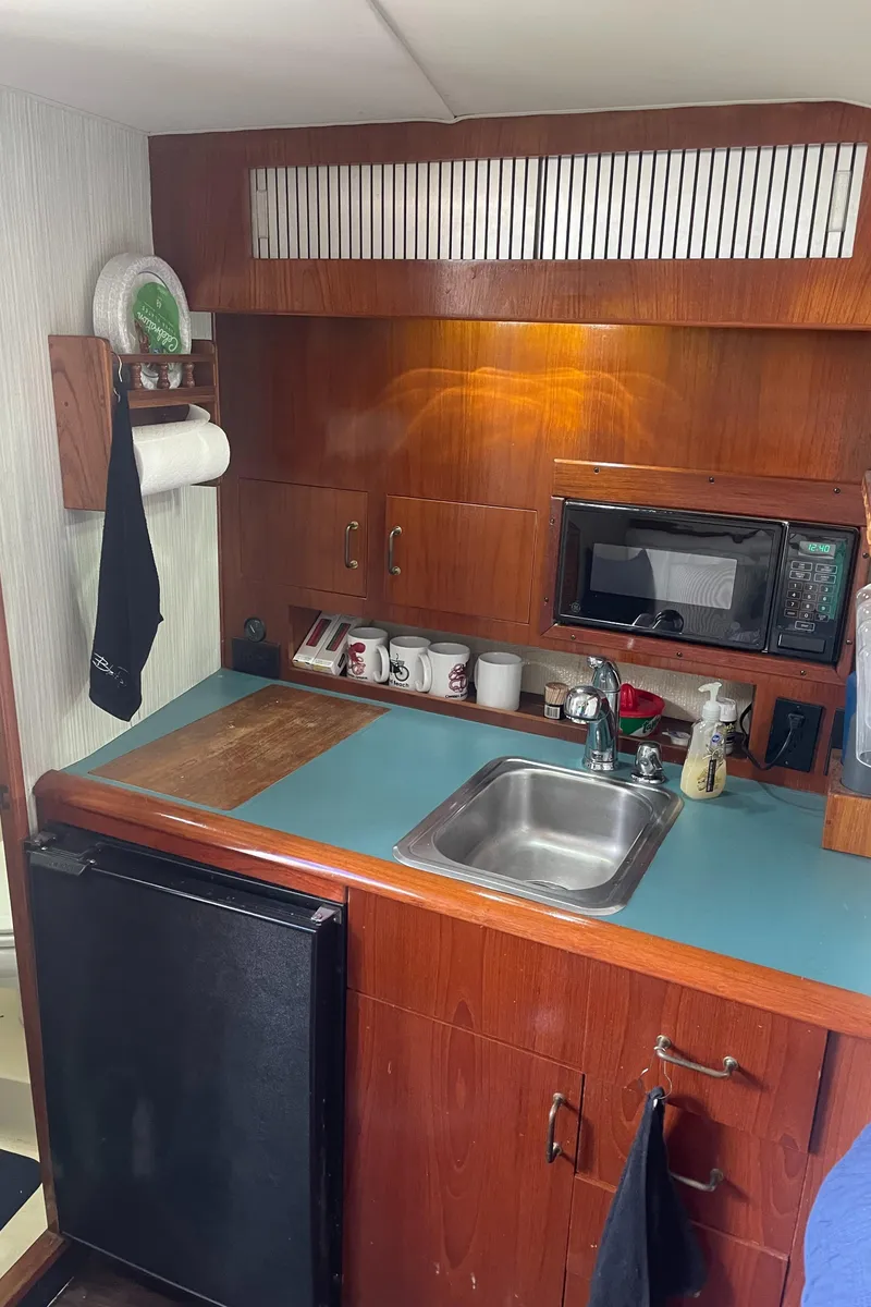 Slide: The Image of 1992 Ocean Yachts Sport Cruiser kitchen with sink, microwave, and wooden cabinetry. - 19
