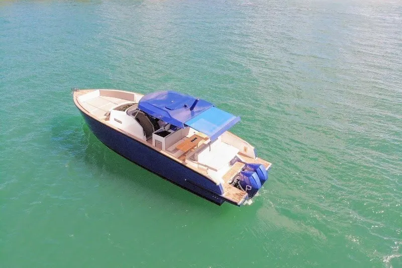 Slide: The Image of 2022 Tesoro T38 Outboard boat on calm green water, featuring a blue canopy. - 14
