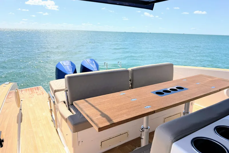 Slide: The Image of 2022 Tesoro T38 Outboard boat with seating and table, overlooking serene ocean view. - 24