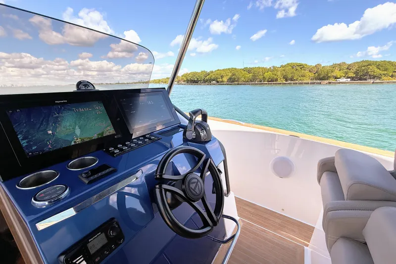 Slide: The Image of 2022 Tesoro T38 Outboard helm with navigation screens, steering wheel, and scenic water view. - 33