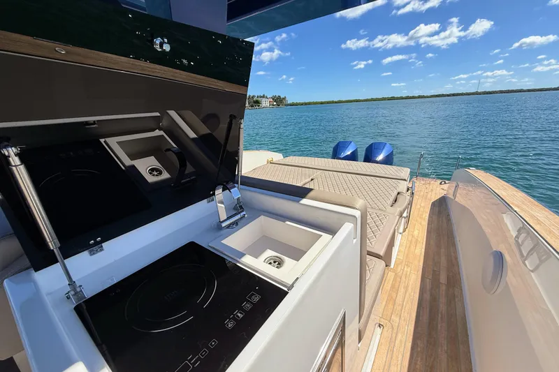 Slide: The Image of 2022 Tesoro T38 Outboard boat with outdoor kitchen and seating, overlooking serene water. - 58