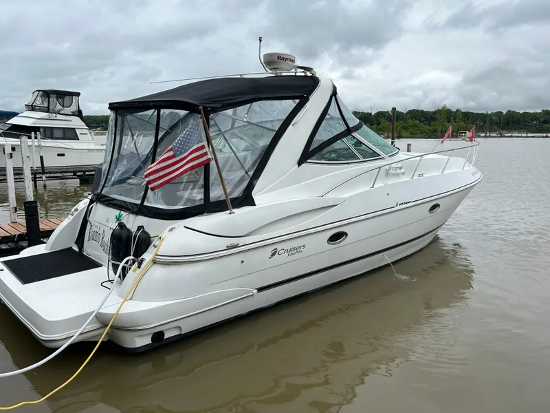 Slide: The Image of 2001 Cruisers Yachts 3470 Express docked, featuring American flag and sleek design. - 0