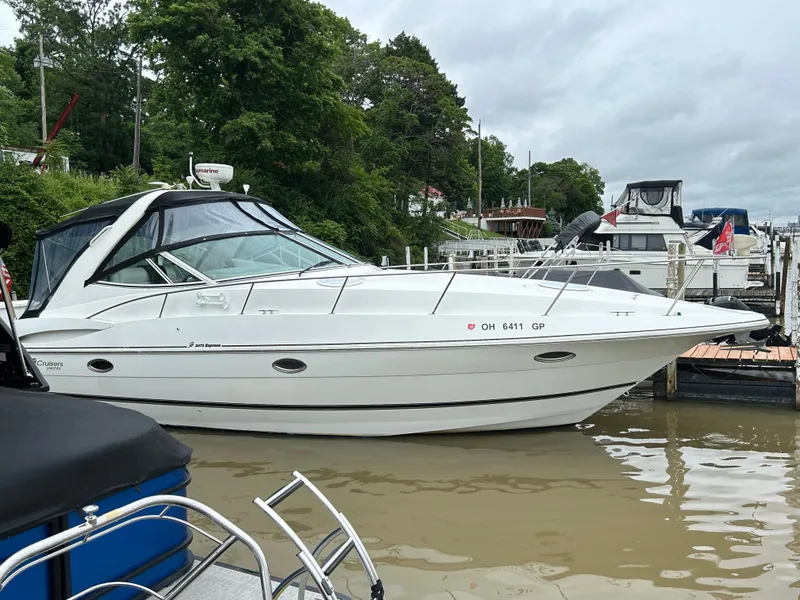 Slide: The Image of 2001 Cruisers Yachts 3470 Express docked at a marina, surrounded by lush greenery. - 1