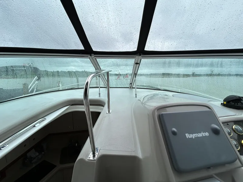 Slide: The Image of 2001 Cruisers Yachts 3470 Express cockpit with rain-covered windshield and Raymarine navigation system. - 27