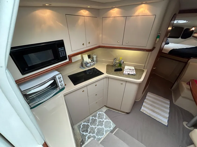 Slide: The Image of 2001 Cruisers Yachts 3470 Express interior kitchen with microwave, stove, and sink. - 29
