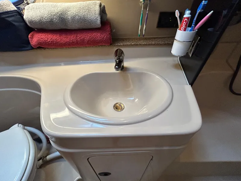 Slide: The Image of Bathroom sink area in a 2001 Cruisers Yachts 3470 Express, with towels and toiletries. - 49