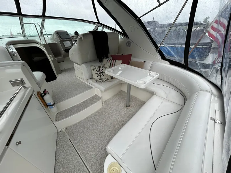 Slide: The Image of 2001 Cruisers Yachts 3470 Express interior with white seating and table, featuring a cozy cabin layout. - 7