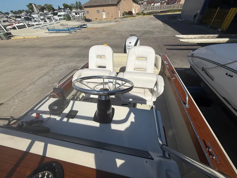 Slide: The Image of 1980 Boston Whaler 22 boat interior with steering wheel and seats at a marina. - 13