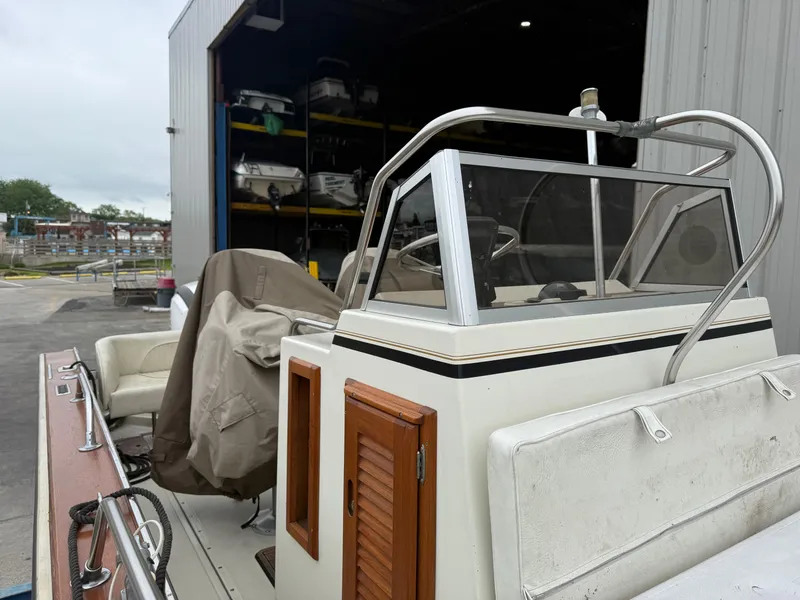 Slide: The Image of 1980 Boston Whaler 22 boat in storage, featuring a covered seating area and wooden accents. - 3