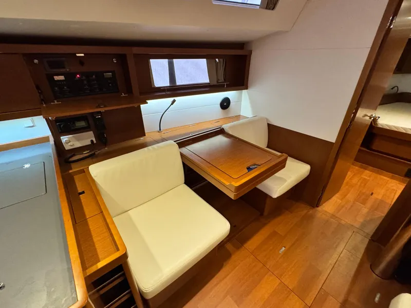 Slide: The Image of 2014 Beneteau Oceanis 48 interior with wooden flooring and cozy seating area. - 22