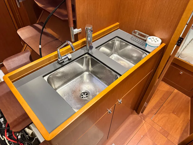 Slide: The Image of 2014 Beneteau Oceanis 48 yacht kitchen with dual stainless steel sinks and wooden cabinetry. - 28