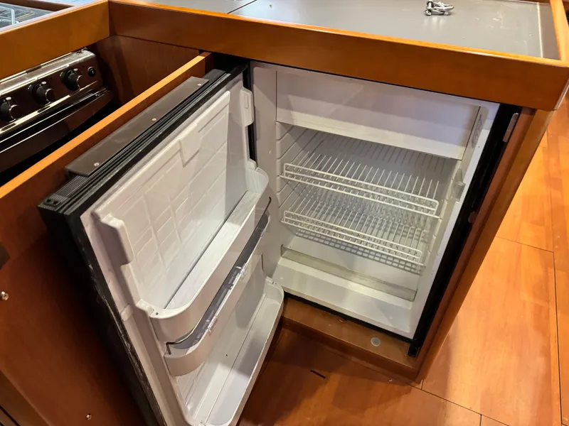 Slide: The Image of Open refrigerator in 2014 Beneteau Oceanis 48 yacht kitchen, featuring wooden cabinetry and stainless steel appliances. - 42