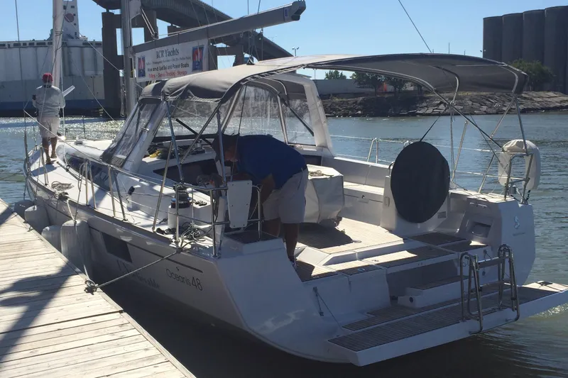 Slide: The Image of 2014 Beneteau Oceanis 48 yacht docked at a marina, featuring a spacious deck and canopy. - 5