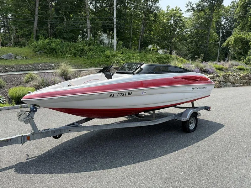 Slide: The Image of 2013 Crownline 185 SS boat on trailer, red and white, parked on road. - 14