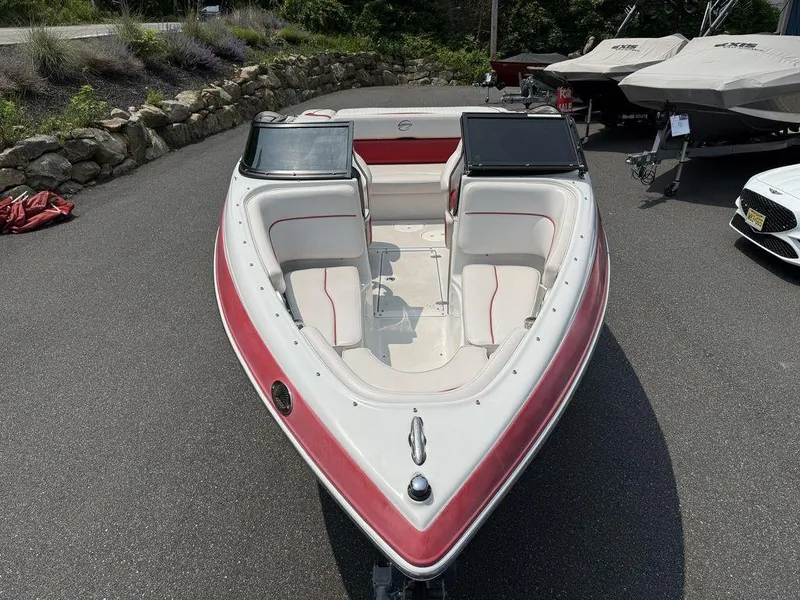 Slide: The Image of 2013 Crownline 185 SS boat with red and white interior, parked on asphalt. - 6