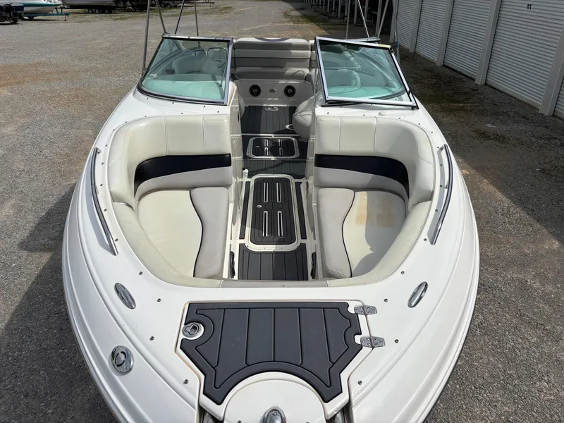 Slide: The Image of 2009 Bryant 268 boat with open bow seating and dual windshields, parked on gravel. - 3