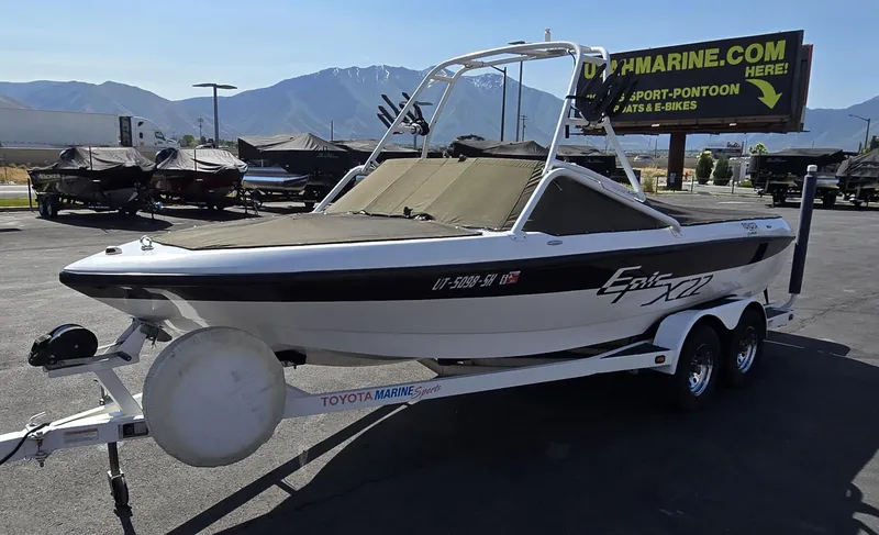 Slide: The Image of 2000 Toyota Epic 22 boat on trailer, parked outdoors with mountains in background. - 7