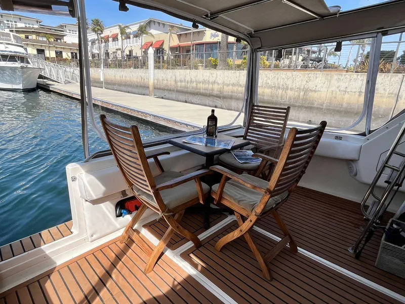 Slide: The Image of 1996 Sea Ray 370 Sedan Bridge yacht with wooden deck and seating area by the water. - 10