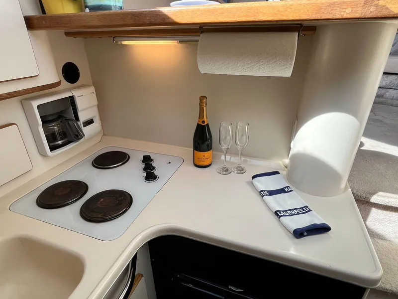 Slide: The Image of 1996 Sea Ray 370 Sedan Bridge kitchen with stove, champagne, and glasses on counter. - 32