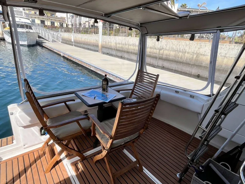 Slide: The Image of 1996 Sea Ray 370 Sedan Bridge interior with wooden chairs and table by the water. - 49