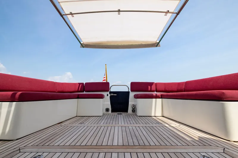 Slide: The Image of 2018 Back Cove Downeast 37 boat deck with red seating and canopy under blue sky. - 15
