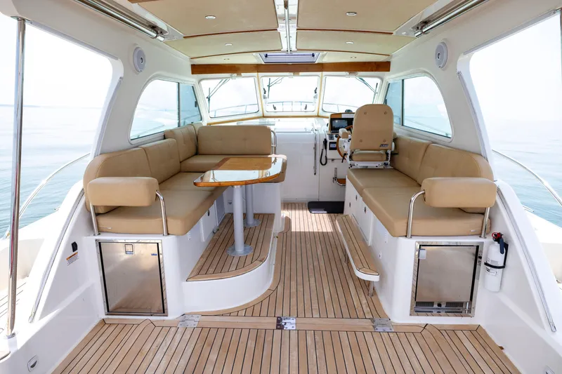 Slide: The Image of 2018 Back Cove Downeast 37 interior with beige seating, wooden flooring, and helm station. - 19