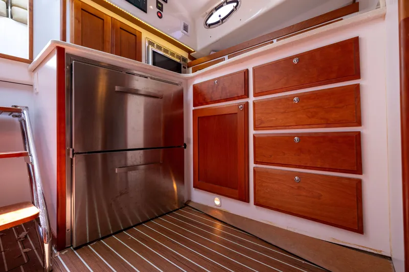 Slide: The Image of 2018 Back Cove Downeast 37 interior with stainless steel fridge and wooden cabinetry. - 35