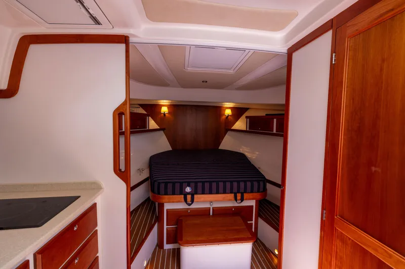 Slide: The Image of 2018 Back Cove Downeast 37 cabin interior with bed, wooden accents, and ambient lighting. - 38