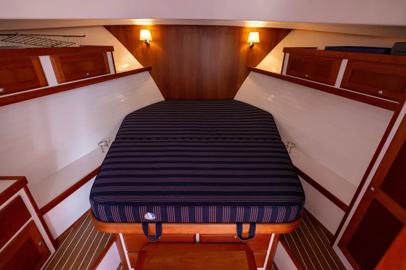 Slide: The Image of 2018 Back Cove Downeast 37 cabin interior with striped bedding and wooden cabinetry. - 39