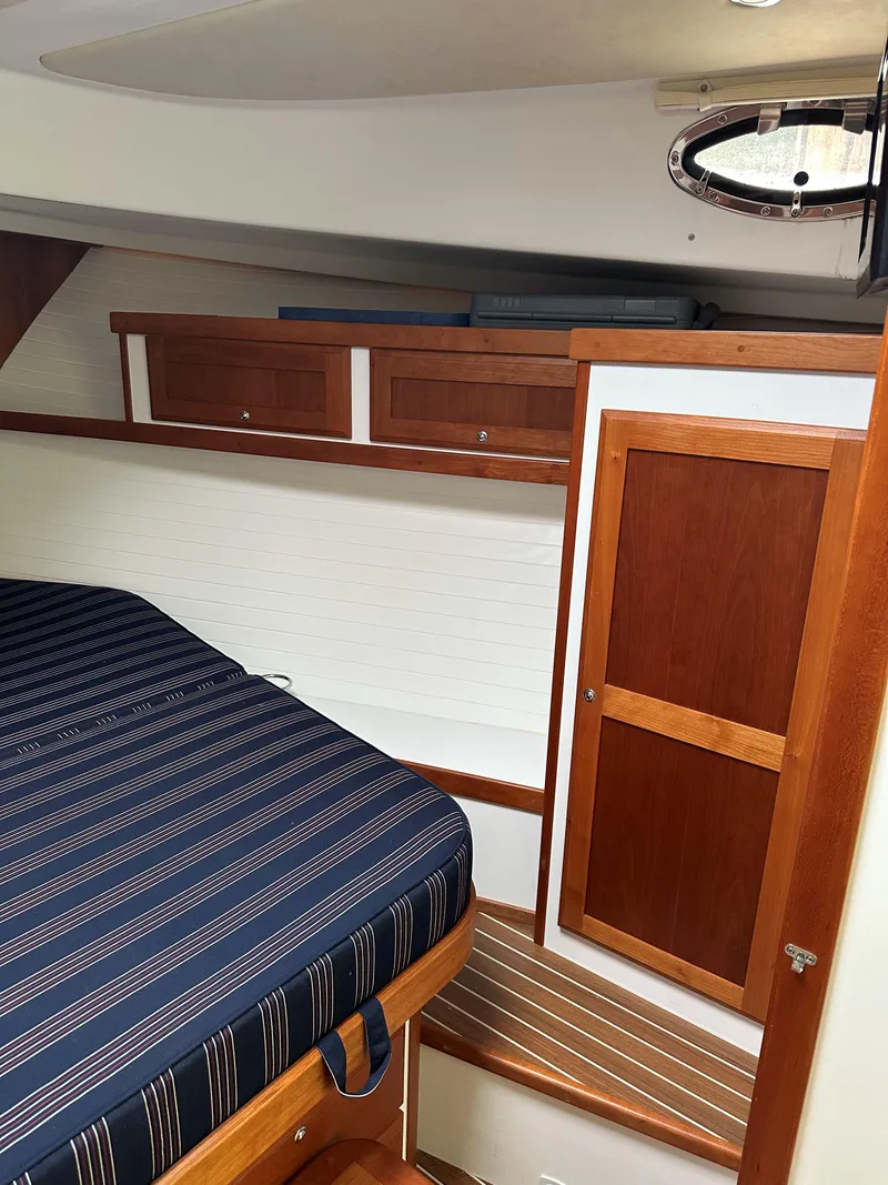 Slide: The Image of 2018 Back Cove Downeast 37 cabin interior with striped bedding and wooden cabinetry. - 41