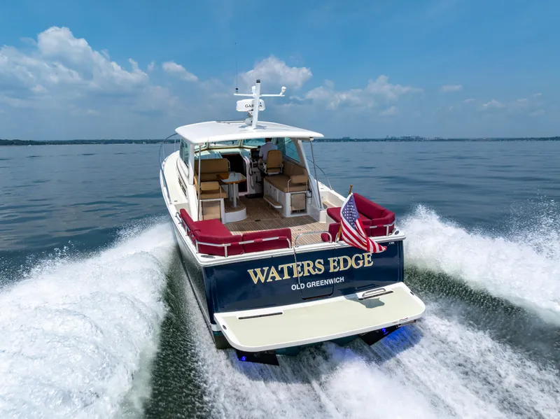 Slide: The Image of 2018 Back Cove Downeast 37 cruising on open water, rear view with American flag. - 6