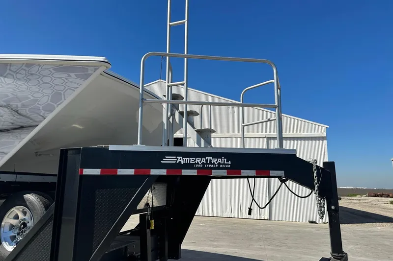 Slide: The Image of Trailer with ladder beside Freeman 47 boat, 2022 model, under clear blue sky. - 100