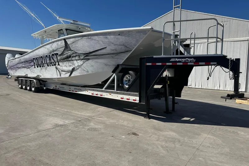 Slide: The Image of 2022 Freeman 47 boat on trailer with marlin graphic, parked outdoors. - 99