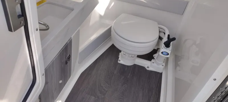 Slide: The Image of 2024 Formula 290 BR boat bathroom with toilet and sink, featuring modern design and wood flooring. - 26