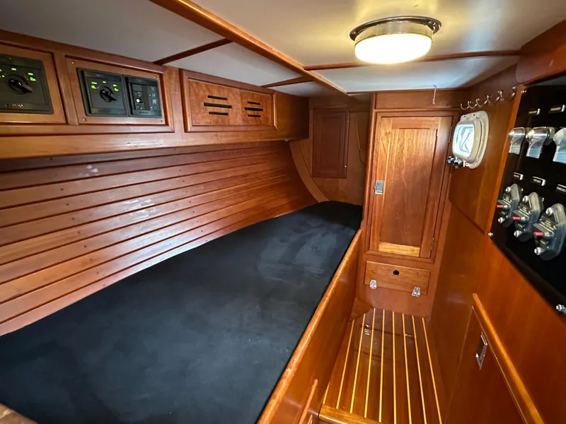 Slide: The Image of 1987 Hinckley Sou'wester 42 cabin interior with wooden paneling and black cushioned berth. - 10