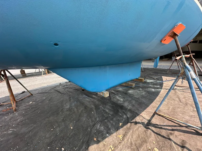 Slide: The Image of 1987 Hinckley Sou'wester 42 sailboat hull on stands, blue finish, outdoor setting. - 34