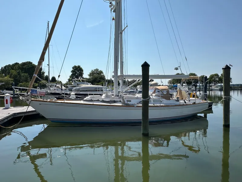 Slide: The Image of 1987 Hinckley Sou'wester 42 sailboat docked in a marina, reflecting on calm water. - 39