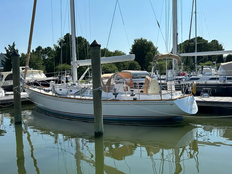 Slide: The Image of 1987 Hinckley Sou'wester 42 sailboat docked in a marina, reflecting on calm water. - 40