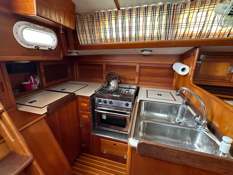 Slide: The Image of 1987 Hinckley Sou'wester 42 yacht kitchen with stove, sink, and wooden cabinetry. - 5
