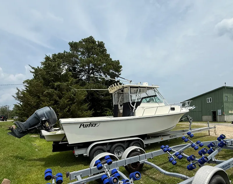 Slide: The Image of 2002 Parker 2510 Walkaround boat on trailer, parked outdoors near trees and a building. - 1
