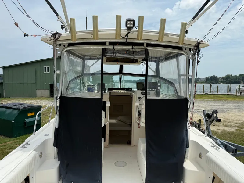 Slide: The Image of 2002 Parker 2510 Walkaround boat with covered cockpit, docked near a waterfront. - 2