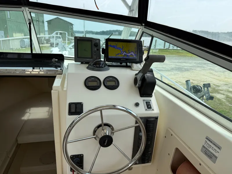 Slide: The Image of 2002 Parker 2510 Walkaround boat dashboard with steering wheel and navigation equipment. - 8