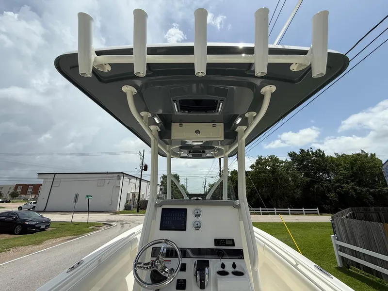 Slide: The Image of 2020 Mako 236 CC boat console with T-top and rod holders, parked outdoors. - 12
