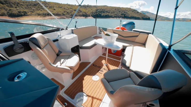 Slide: The Image of 2025 Ventura V195 Crossover boat interior with seating, table, and scenic lake view. - 4