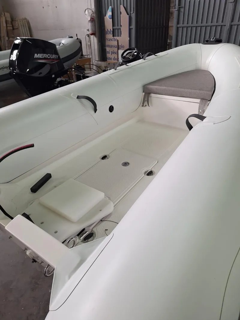 Slide: The Image of 2025 Geniuss 330 Cruiser inflatable boat with Mercury outboard motor in a garage setting. - 24