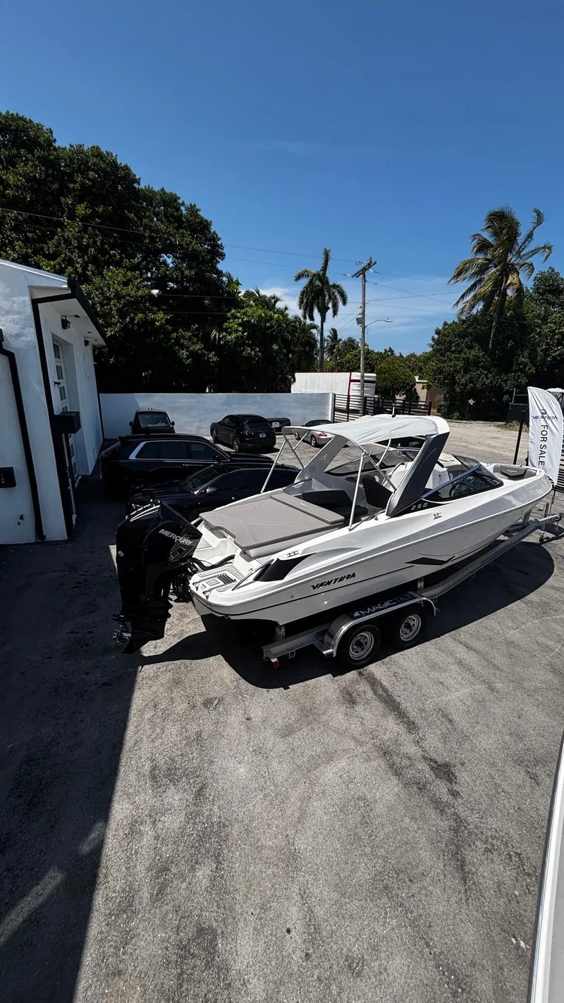 Slide: The Image of 2025 Ventura V250 Comfort boat on trailer, parked outdoors under clear blue sky. - 2