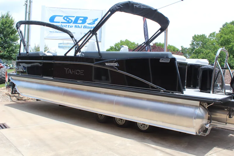 Slide: The Image of 2025 Tahoe Pontoon Cascade Quad Lounger, black exterior, displayed outdoors at a dealership. - 2